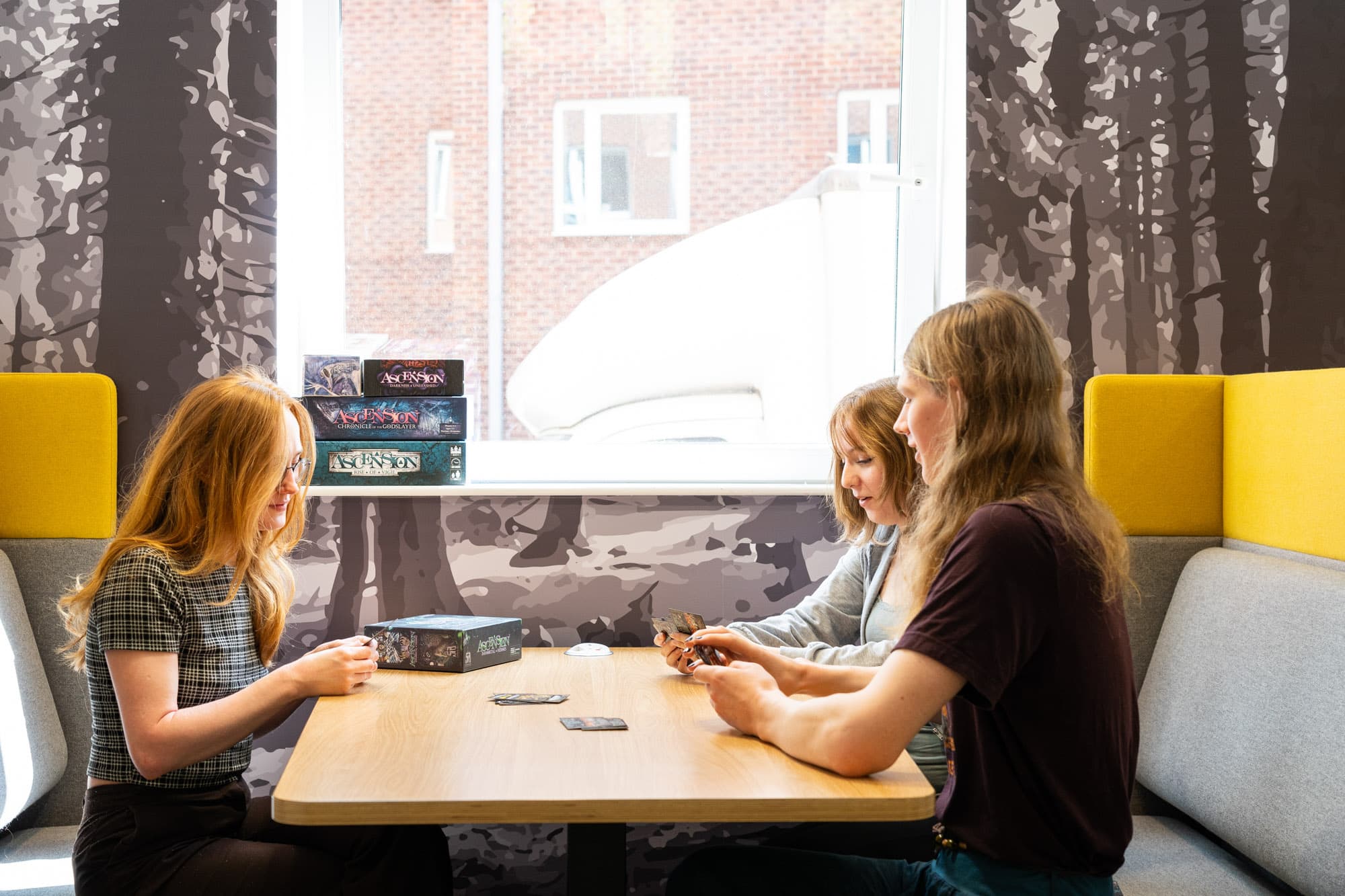 Two students playing a board game at a table in a social space